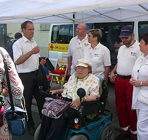 DRK-Mitarbeiter und Rollstuhlfahrerin am DRK-Infostand