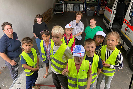 Gruppenbild mit Betreuerinnen und 8 Kindern neben einem Rettungswagen