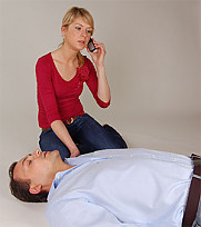 Frau kniet neben einem Mann auf dem Boden und telefoniert