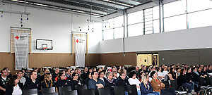 Teilnehmer in bestuhlter Halle hören einen Vortrag