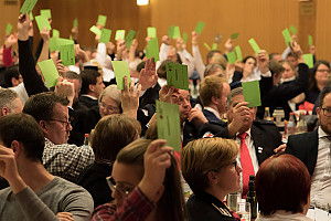 Abstimmung bei der Versammlung: Teilnehmerinnen halten grüne Zettel hoch