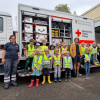 Gruppenbild mit Kindern und Betreuerinnen vor einem Rettungswagen