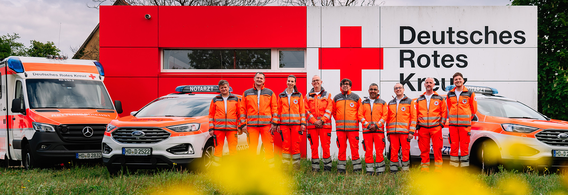 Gruppenbild Rettungssanitäter vor einer Rettungswache und neben Rettungsfahrzeugen