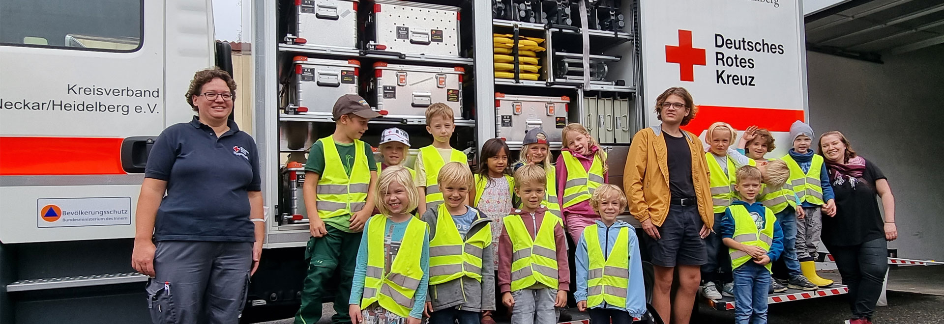 Gruppenbild mit Kindern und Betreuerinnen vor einem Rettungswagen