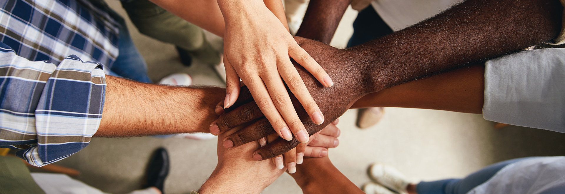 übereinander gestapelte Hände verschiedener Menschen mit unterschiedlicher Hautfarbe