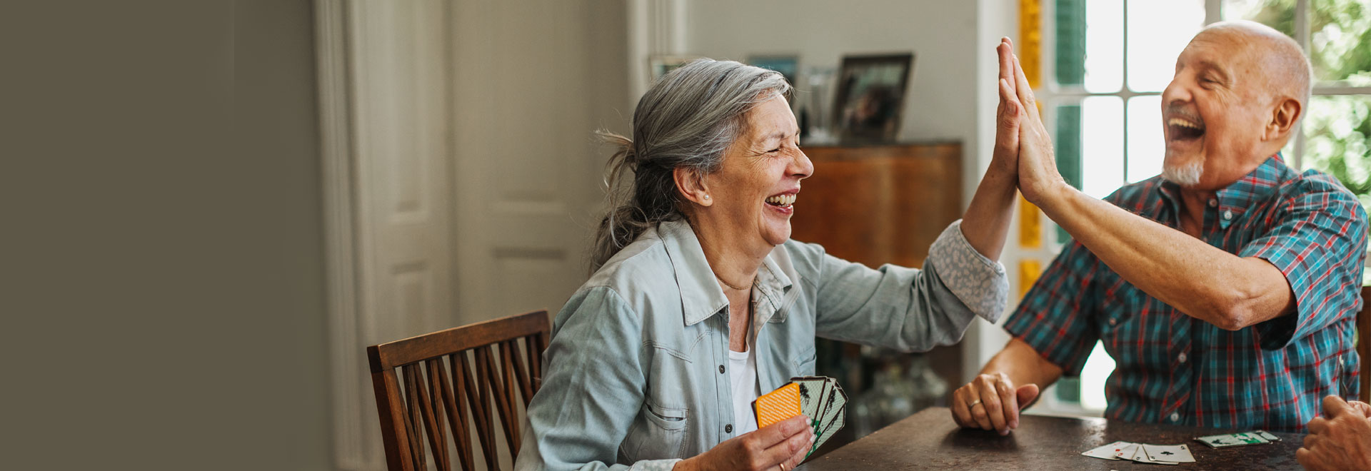 Eine Seniorin und ein Senior an einem Tisch beim Kartenspielen