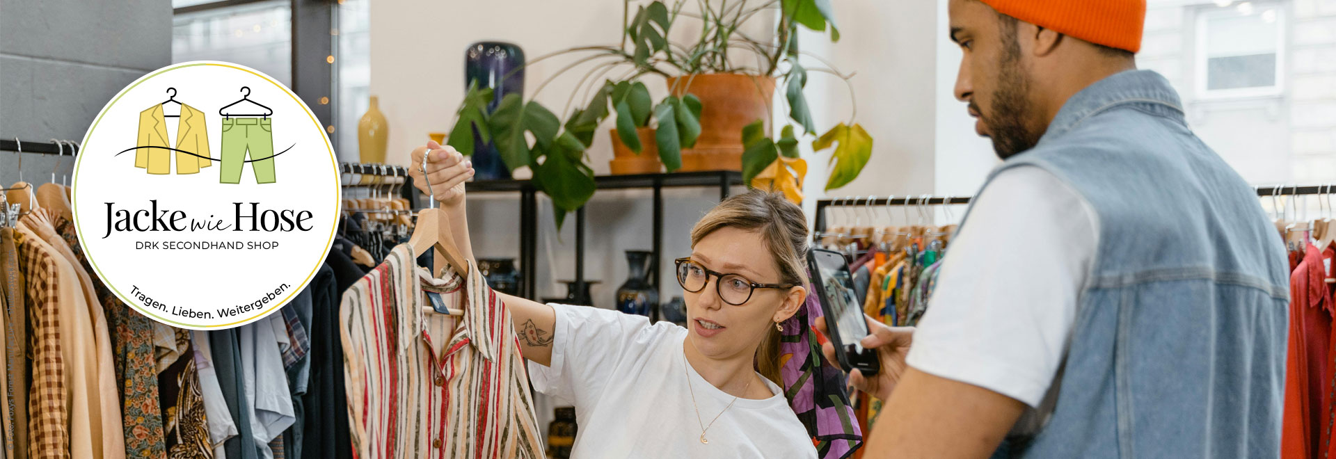 Eine junge Frau zeigt einem Kunden ein gestreiftes Hemd