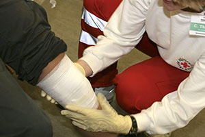 DRK Mitarbeiterin legt einen Verband am Knie eines Patienten an