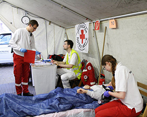 DRK-Mitarbeiter bei der Betreuung eines Verletzten in einem Zelt