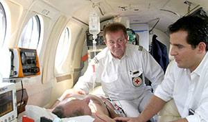 Zwei Rettungssanitäter versorgen einen Patienten im Flugzeug