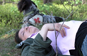 Verletzte Frau im Wald mit Rettungshund
