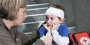 Frau versorgt ein Kind mit einem Kopfverband