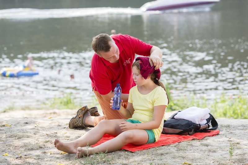 Sanitäter kühlt den Kopf eines Mädchens an einem See..