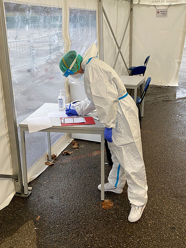 DRK-Mitarbeiter in Schutzkleidung notiert etwas in eine Liste