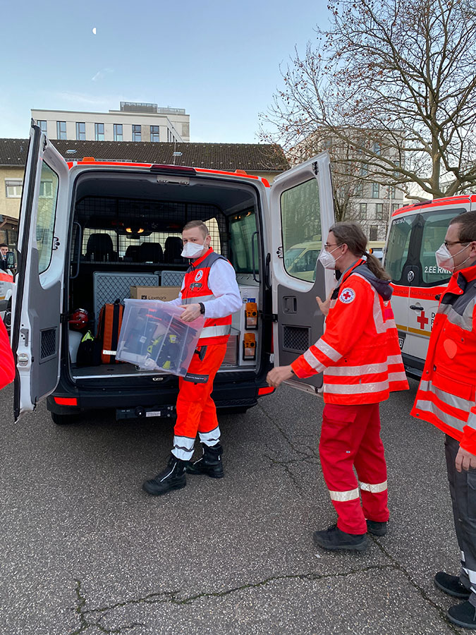DRK-Mitarbeiter des Mobilen Impfteams beim Beladen des DRK-Fahrzeugs