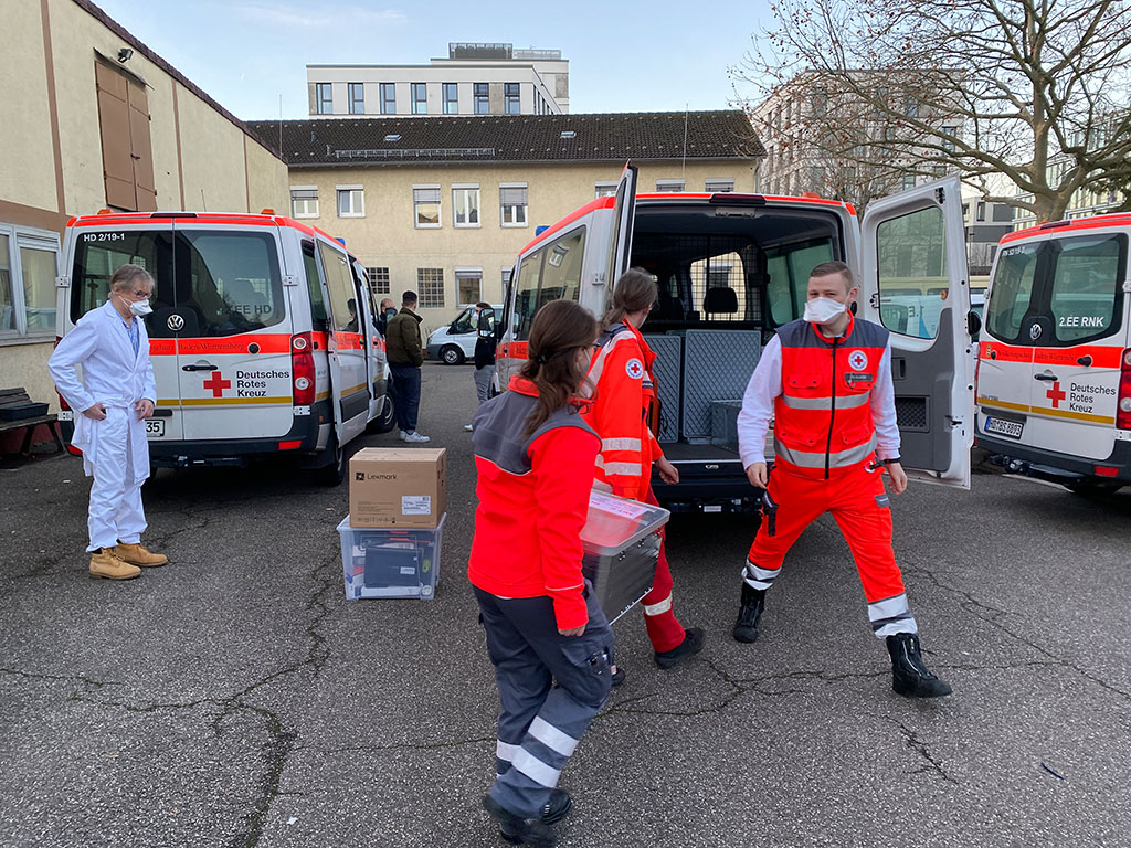 DRK-Mitarbeiter des Mobilen Impfteams beim Beladen des DRK-Fahrzeugs