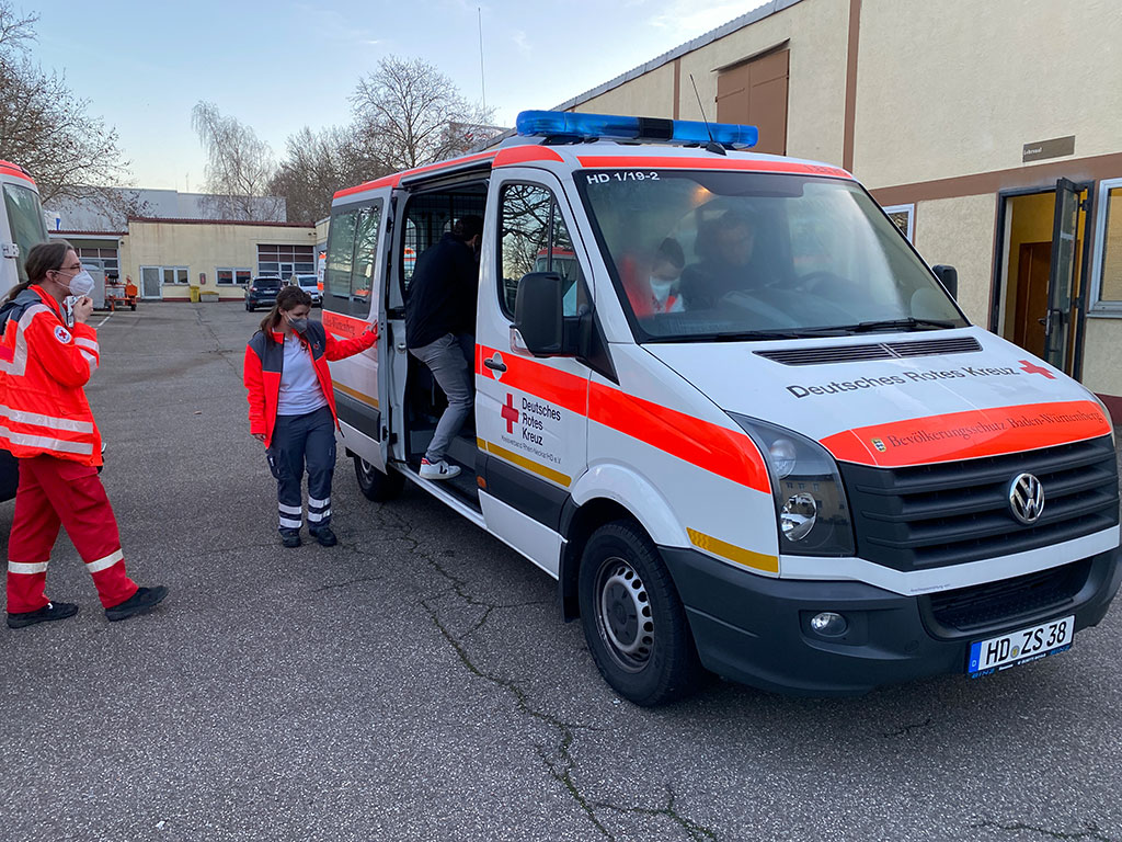 DRK-Mitarbeiter des Mobilen Impfteams steigen in ein DRK-Fahrzeug