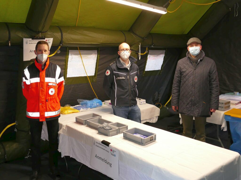 DRK-Mitarbeiter mit Masken in einer Teststation