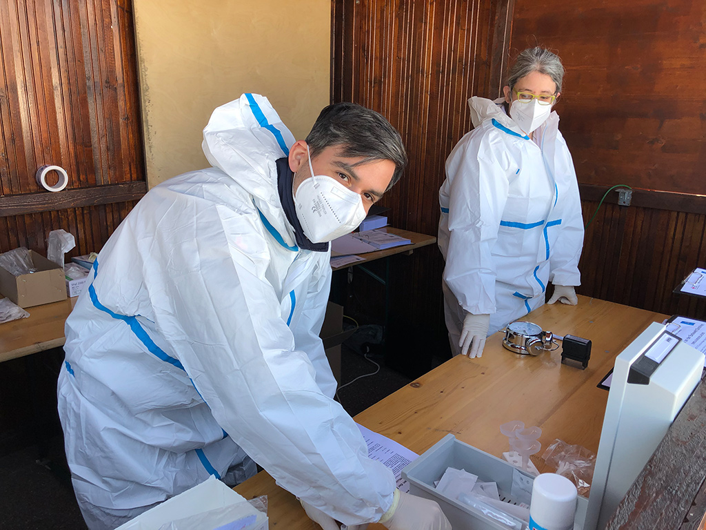 Zwei DRK-Mitarbeiter mit Schutzkleidung an einem Tisch