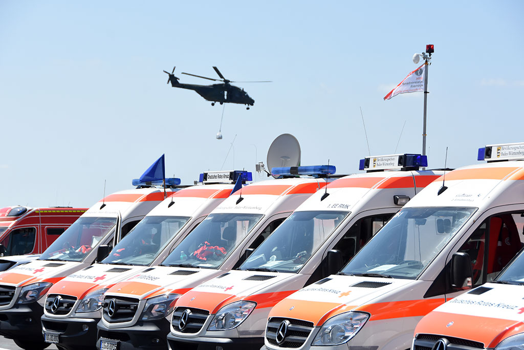 Nebeneinander geparkte DRK-Fahrzeuge und ein Hubschrauber