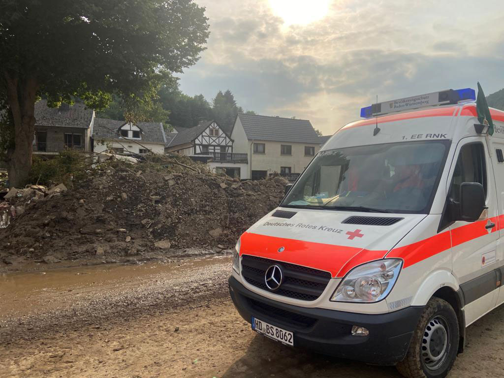 DRK-Fahrzeug des Bevölkerungsschutzes auf der Straße neben Schutthaufen