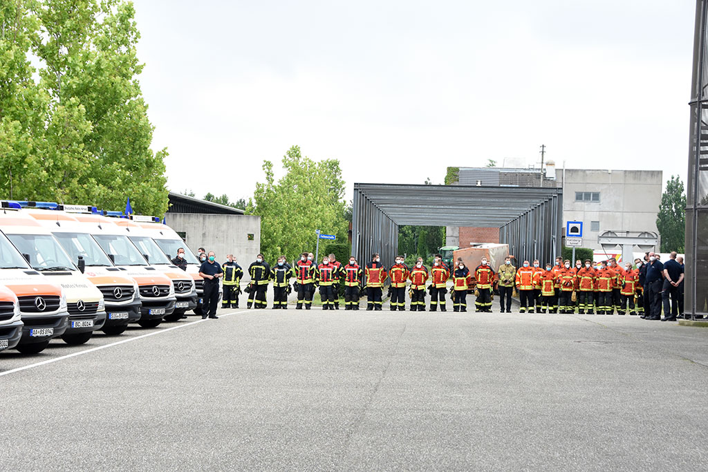 Großes Gruppenbild mit Helfern und geparkten DRK-Fahrzeugen