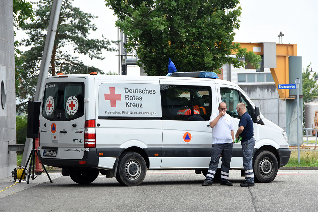 Zwei DRK-Mitarbeiter unterhalten sich vor einem DRK-Fahrzeug