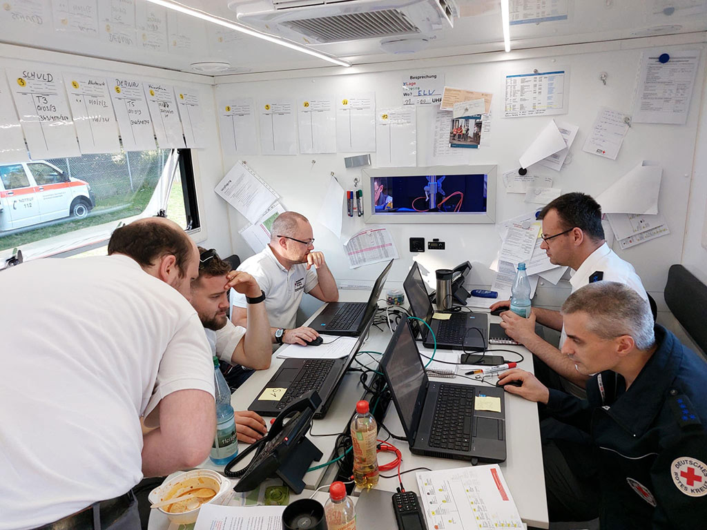Fünf Männer in einer provisorischen Einsatzzentrale mit Laptops