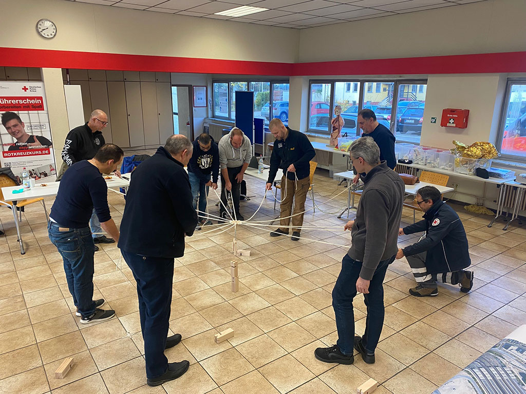 Teilnehmer ziehen gemeinsam an verschiedenen Seilen um einen Gegenstand zu platzieren