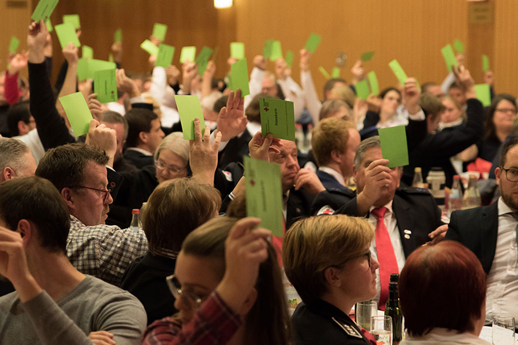 Abstimmung bei der Versammlung: Teilnehmerinnen halten grüne Zettel hoch