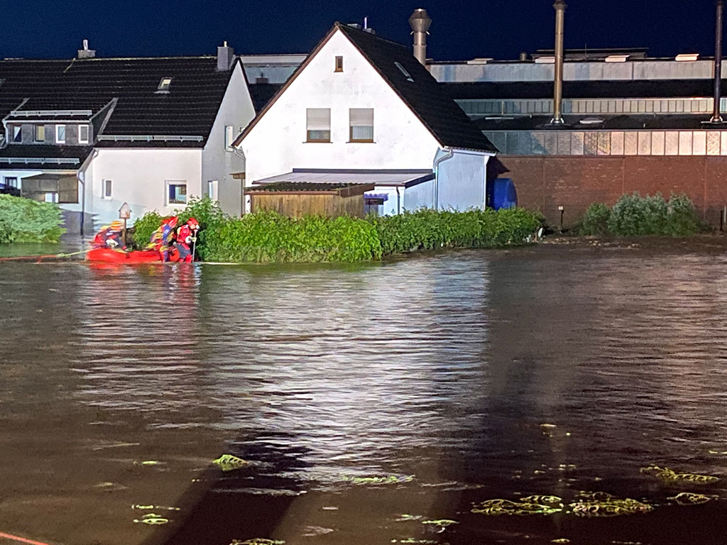 DRK-Mitarbeiter in einem Schlauchboot auf überfluteter Straßeer