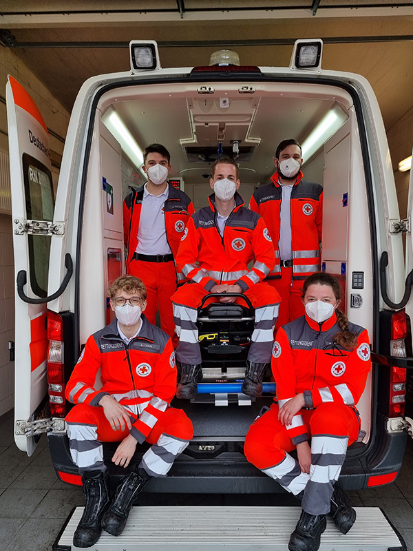 Die fünf neuen Azubis - sitzend im geöffneten Rettungswagen