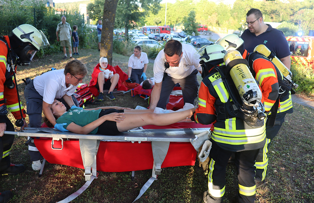 Mehrere Sanitäter-innen legen eine Verletzte auf eine Trage