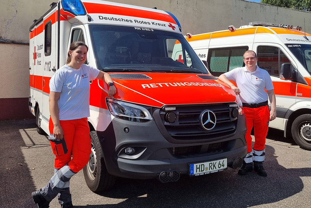 Zwei JRKler*innen neben einem Rettungswagen