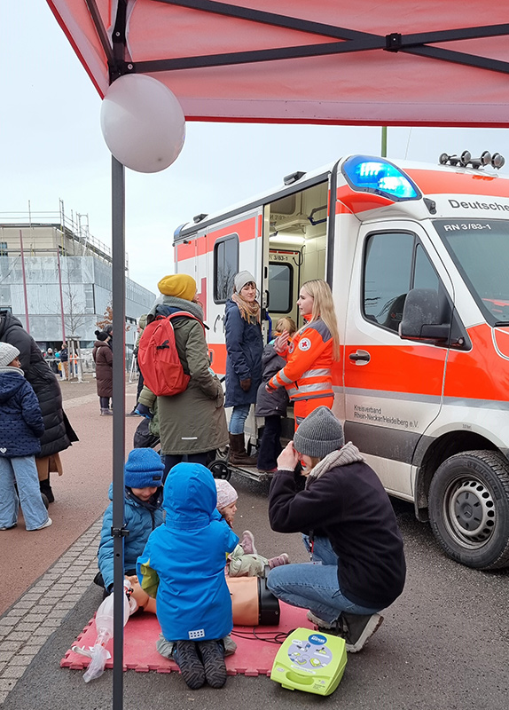 Interessierte Festbesucher schauen sich einen Rettungswagen an und informieren sich bei einer DRK-Mitarbeiterin