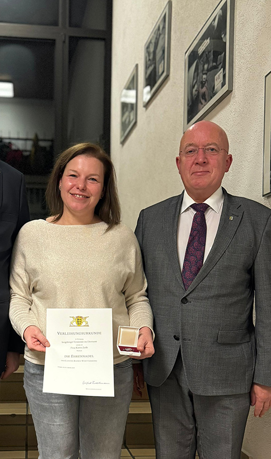Katrin Ziefle steht neben Bürgermeister Ludwig Sauer und zeigt ihre Ehrennadel und ihre Urkunde