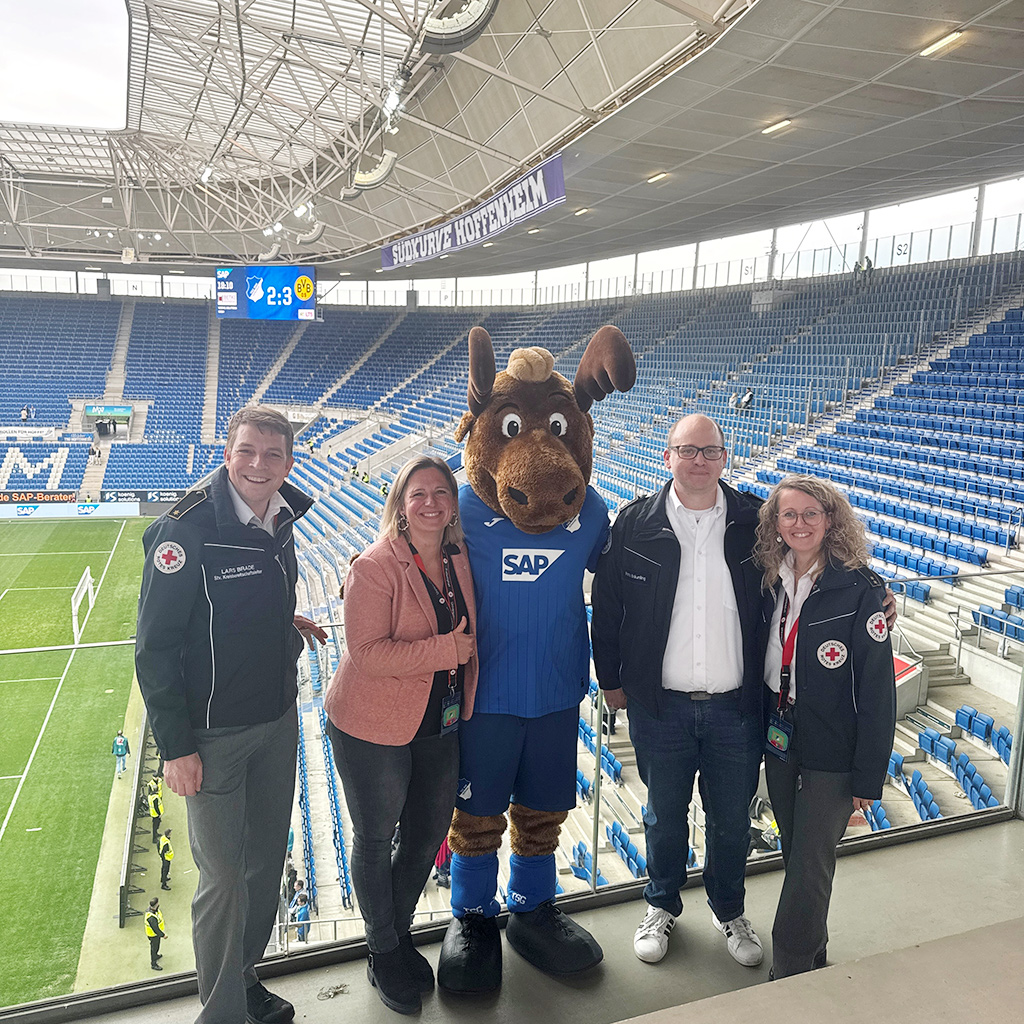 Der stellvertretende Kreisbereitschaftsleiter Lars Brade, Kreisgeschäftsführerin Caroline Falk, TSG-Hoffenheim-Maskottchen „Hoffi“ und Kreisbereitschaftsleiterin Yvonne Wiedl bedanken sich bei Patrick Bräunling