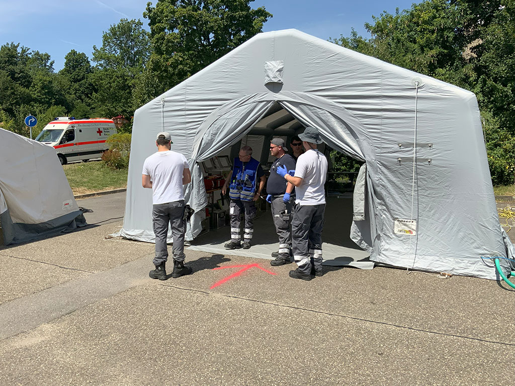 Vier Helfer vor einem Sanitätszelt
