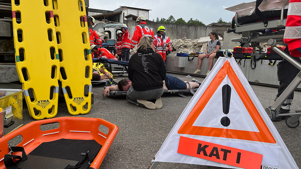 Warndreieck mit der Aufschrift KAT 1 vor verletzten Personen und Sanitätern