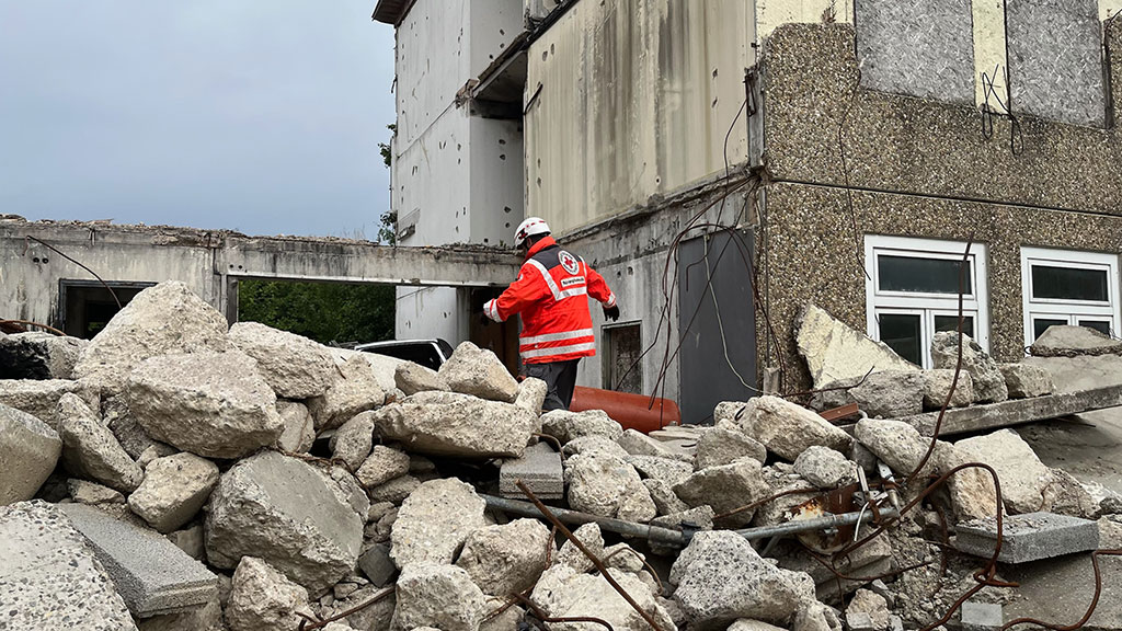 Ein Mitarbeiter des Bevölkerungsschutzes klettert über große Schuttberge