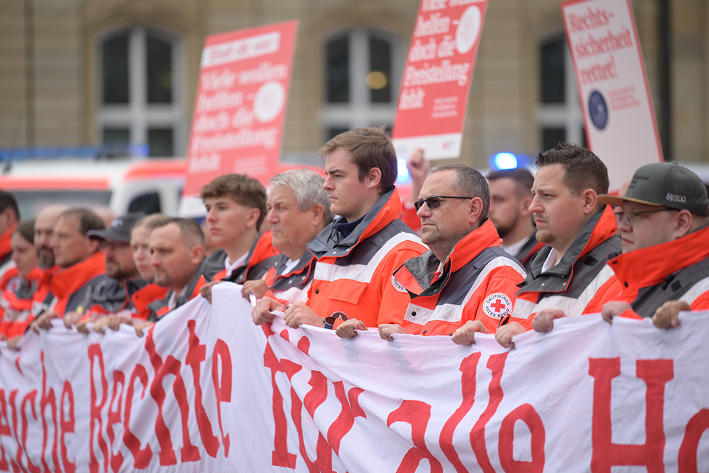 Mitglieder des DRK halten Banner und Plakate hoch