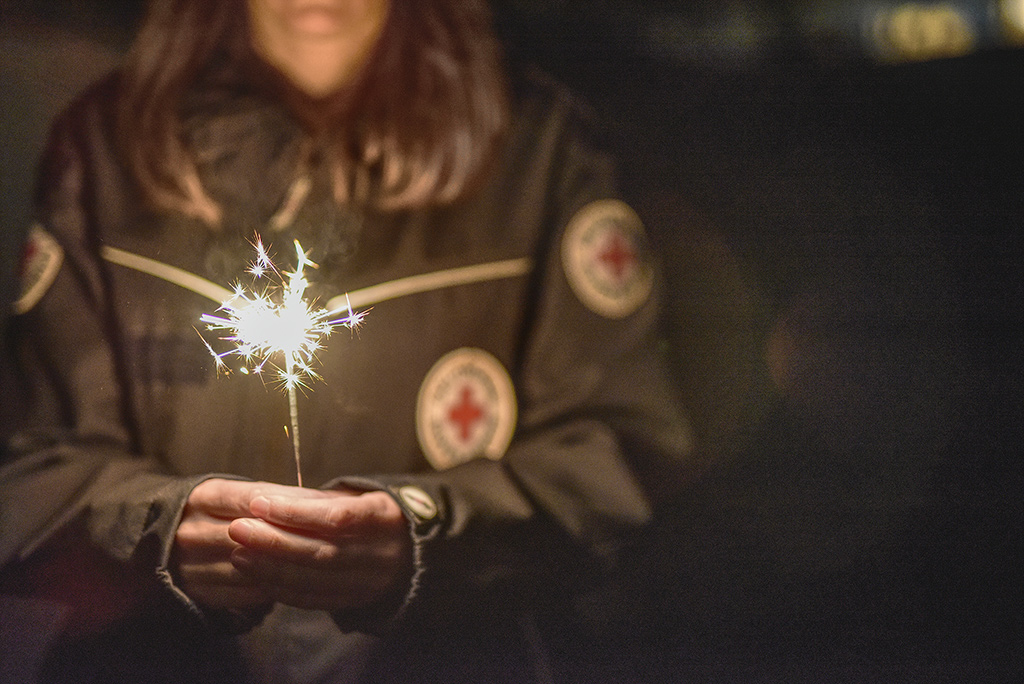 DRK-Mitarbeiterin hält mit beiden Händen eine brennende eine Wunderkerze