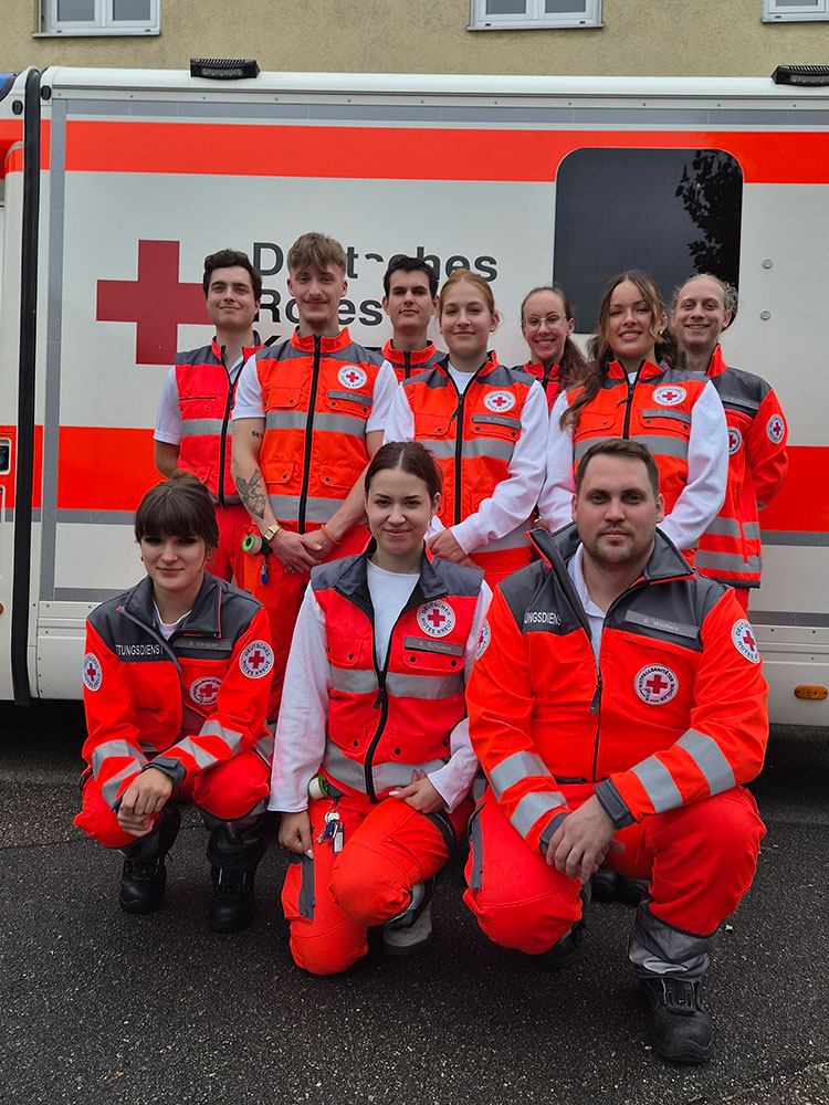 Gruppenbild mit zehn neuen NotSan-Azubis vor einem Rettungswagen