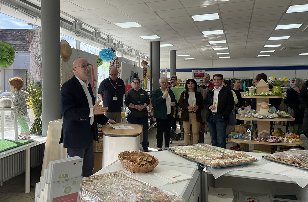 Jürgen Wiesbeck hält eine Rede und verschiedene Menschen hören stehend zu