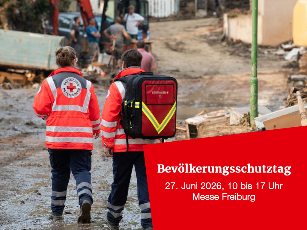 Zwei DRK-Helfer waten durch Schlamm; Info Bevölkerungsschutztag 27.6., Messe Freiburg