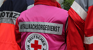 Rettungssanitäter mit dem Rücken zum Betrachter, Jacke mit der Beschriftung Notfallnachsorgedienst
