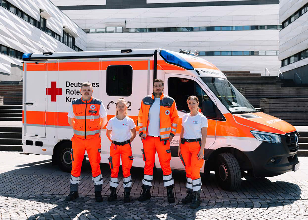 Vier-köpfiges Team des DRK Retungsdienstes steht vor einem Rettungswagen