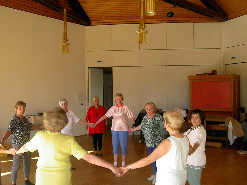 Seniorinnen bei der Gymnastik halten sich im Kreis an den Händen