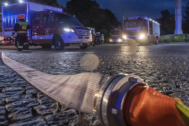 Feuerwehrschlauch im Vordergrund, im Hintergrund Rettungsfahrzeuge