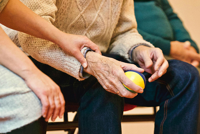 Informationen zu Aktivierenden Hausbesuchen DRK-Mitarbeiterin aktiviert einen Senior mit einem Ball